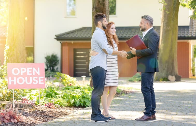 L'agente immobiliare saluta una giovane coppia in una casa aperta